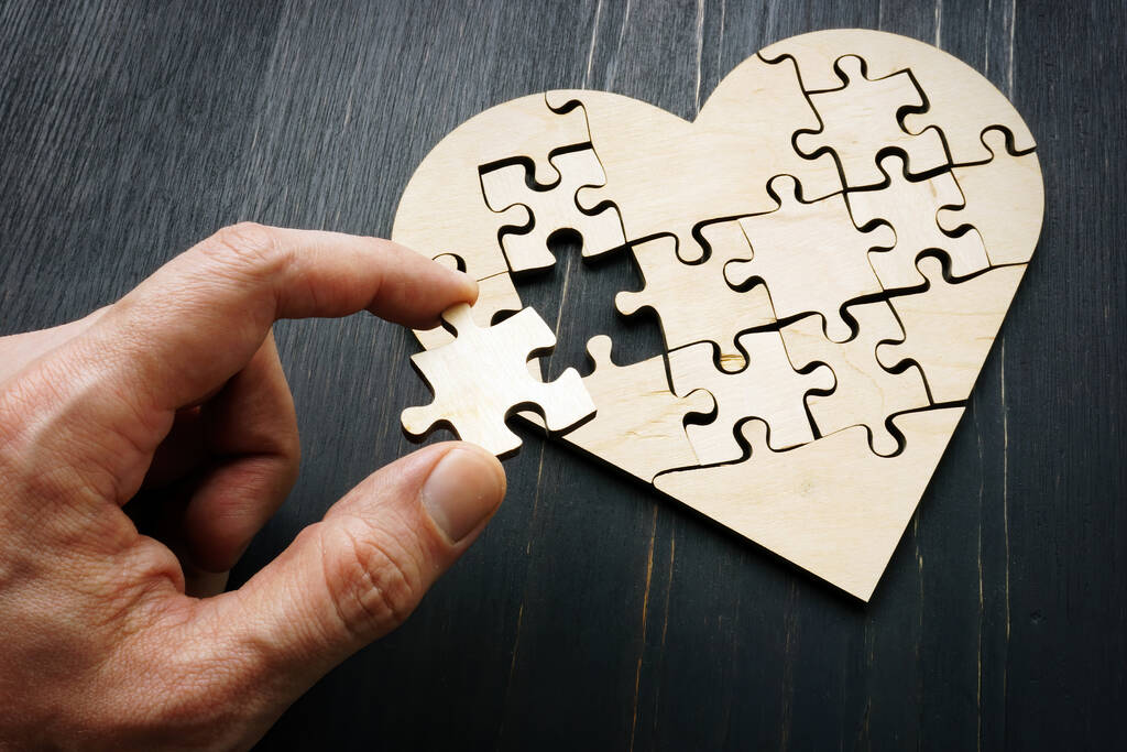 La main tient une pièce du puzzle sous la forme d'un cœur. - Photo, image