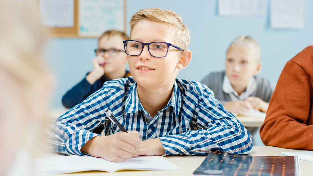 Ve třídě základní školy: Portrét brilantního bělocha s brýlemi píše do sešitu cvičení. Diverse Group of Bright Children Learning Science and Creative Thinking - Fotografie, Obrázek