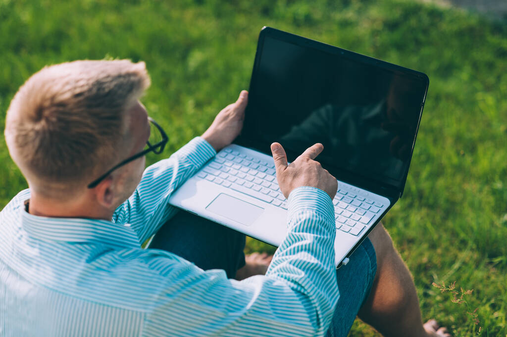 Geschäftsmann mit blauer Jacke vor grauem Hintergrund und Laptop in der Hand - Foto, Bild