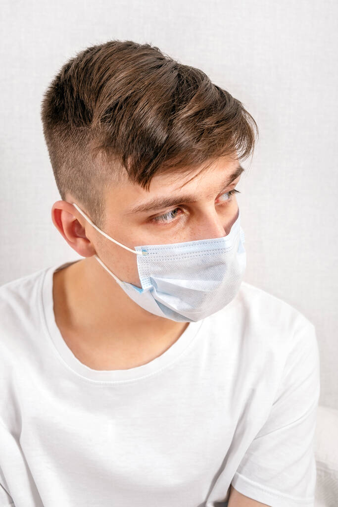 Egy fiatal férfi portréja influenza maszkban a Fal mellett a szobában. - Fotó, kép