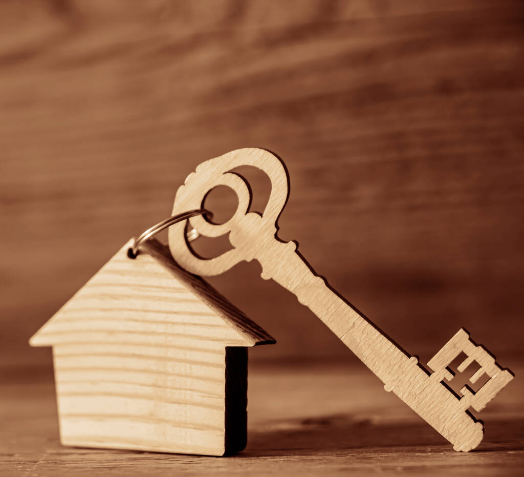 House key with trinket on wooden background, empty copy space for inscription. - Photo, Image