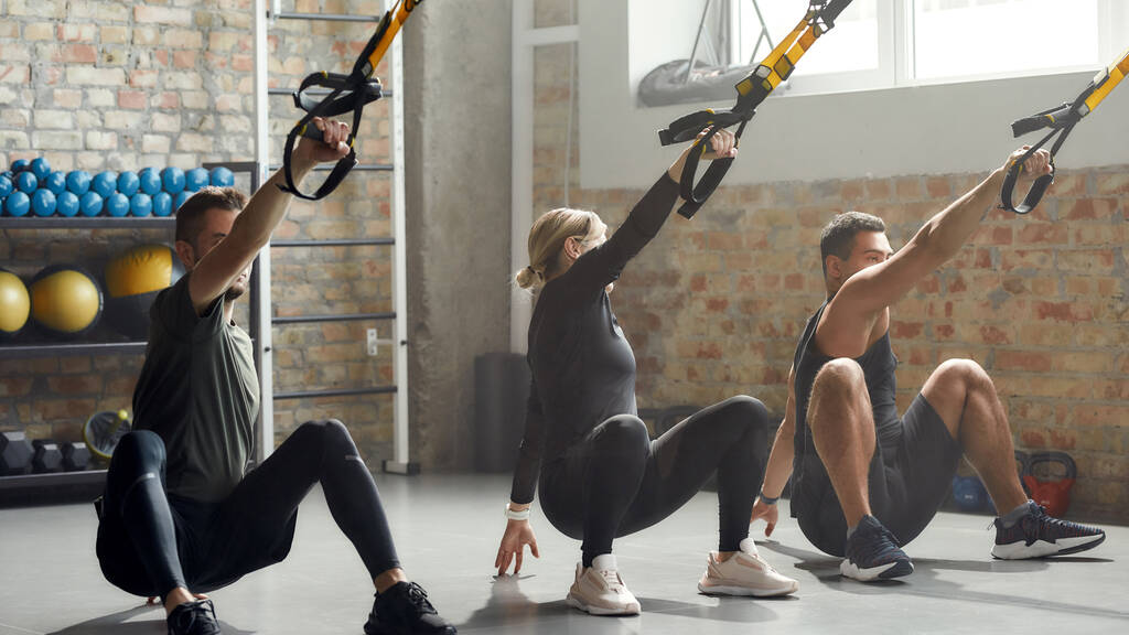 Next Level Fitness. Full-length shot of men and women doing fitness training exercises at industrial gym. Push-up, group workout concept - Photo, Image