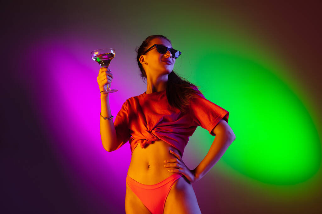 Hermosa chica seductora en traje de baño de moda en discoteca bicolor fondo de estudio de neón en luz de neón. Verano, resort, moda y concepto de fin de semana
 - Foto, imagen