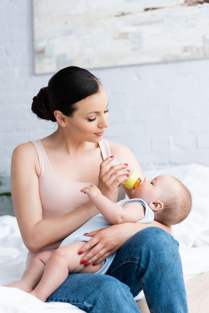 bela mulher alimentando bonito bebê menino enquanto segurando bebê garrafa
 - Foto, Imagem