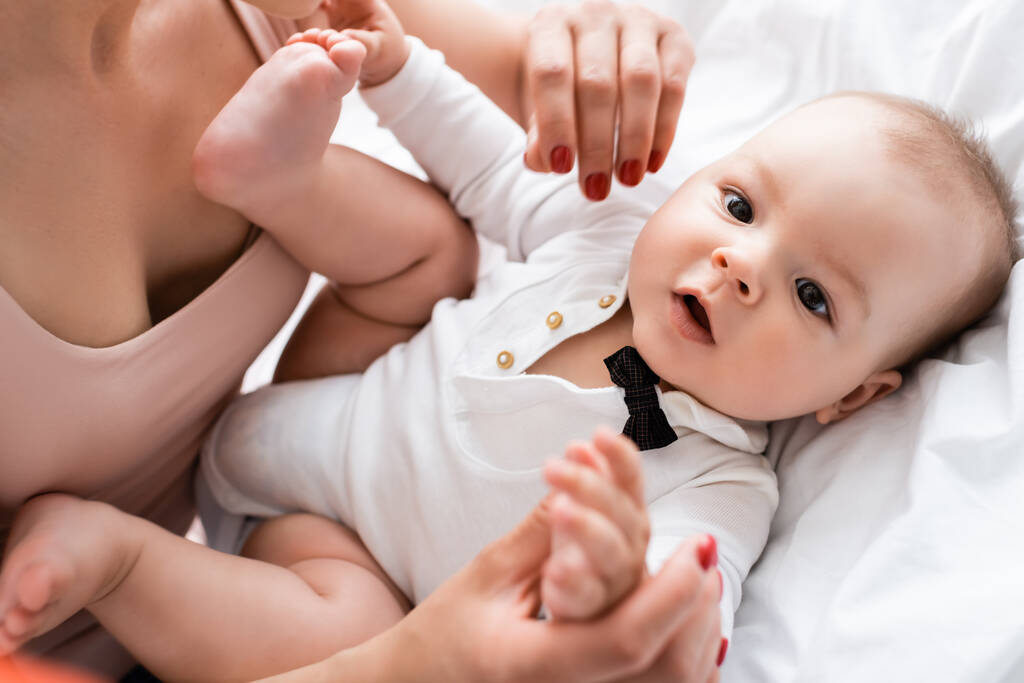 вибірковий фокус матері торкається босоніж немовляти сина на ліжку
 - Фото, зображення
