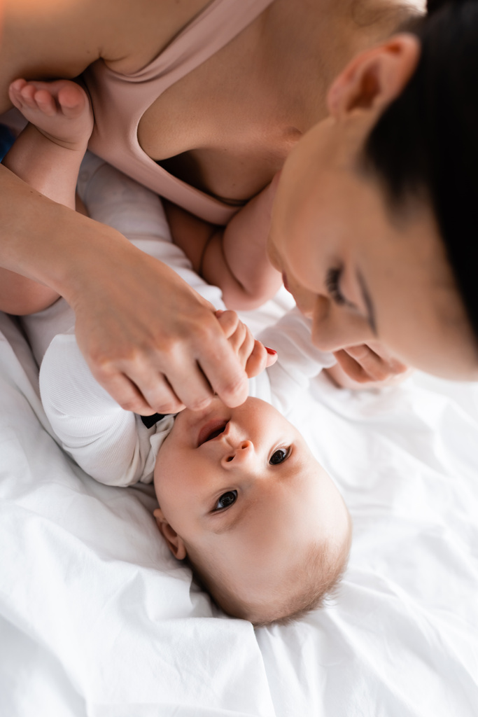 вибірковий фокус матері торкається немовляти сина на ліжку
 - Фото, зображення