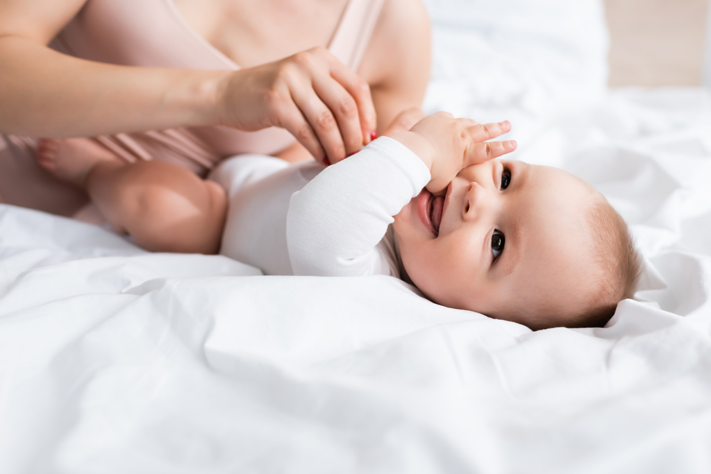 valikoiva painopiste äiti koskettaa onnellinen pikkulapsi poika vauva romper sängyssä - Valokuva, kuva