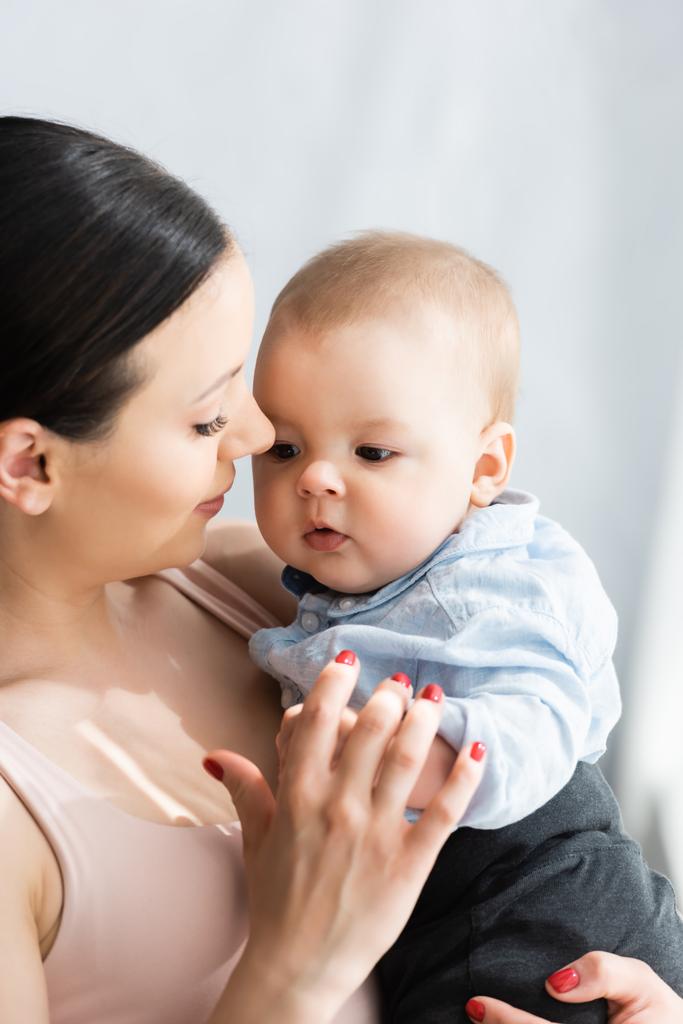 hermosa madre sosteniendo en brazos lindo bebé hijo en ropa de bebé
  - Foto, Imagen