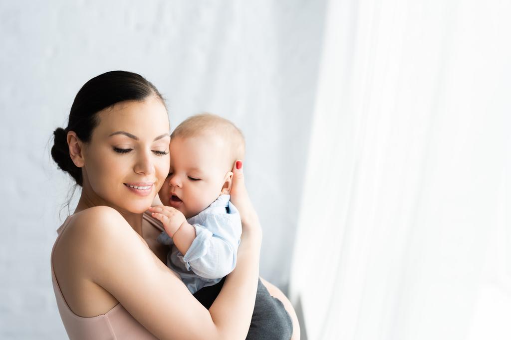 happy mother holding in arms cute infant son in baby clothing  - Photo, Image