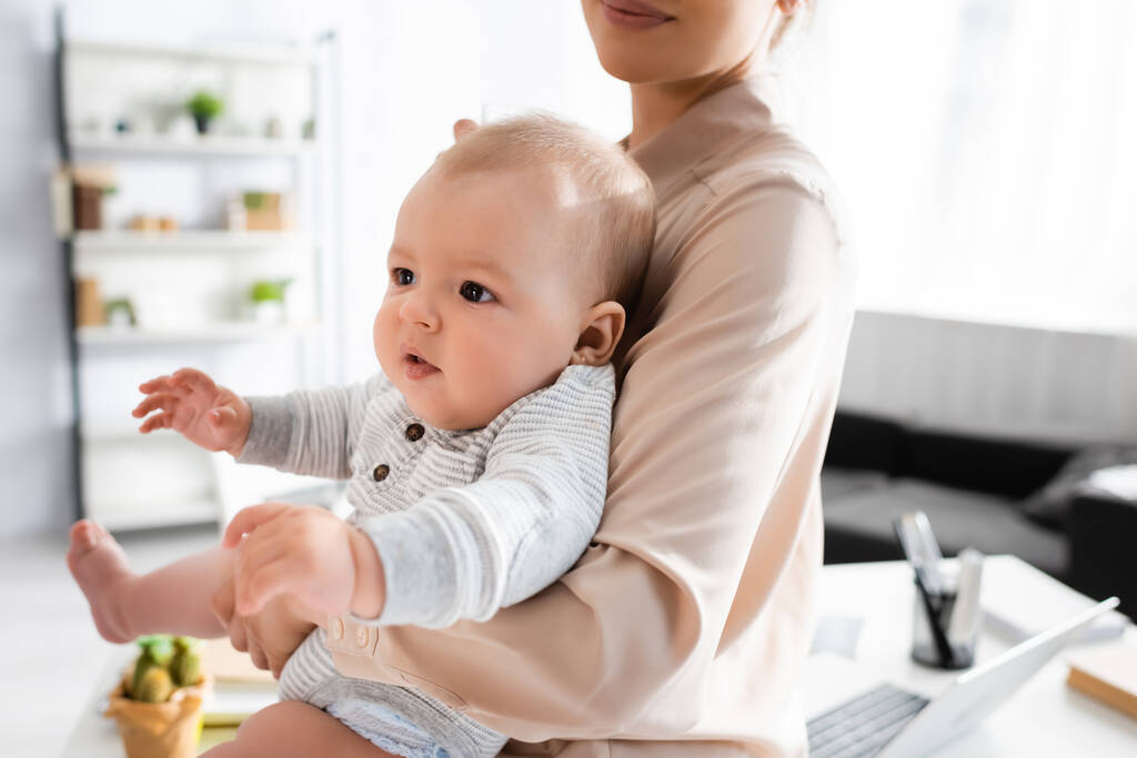 Mutter hält entzückenden Säugling zu Hause im Arm - Foto, Bild