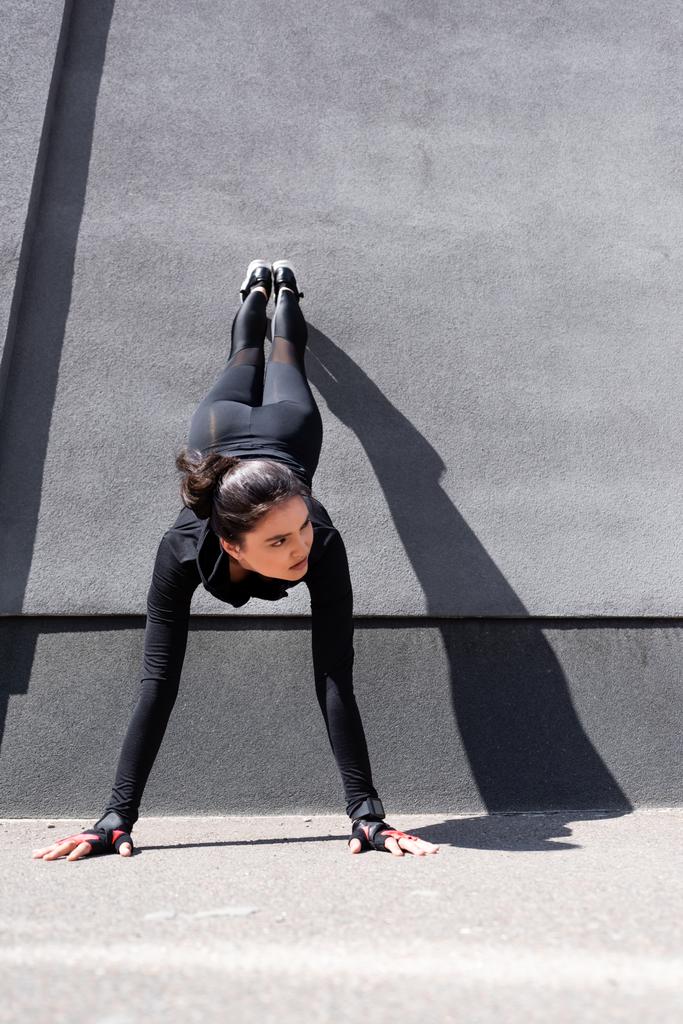 young sportswoman working out near concrete wall - Photo, Image