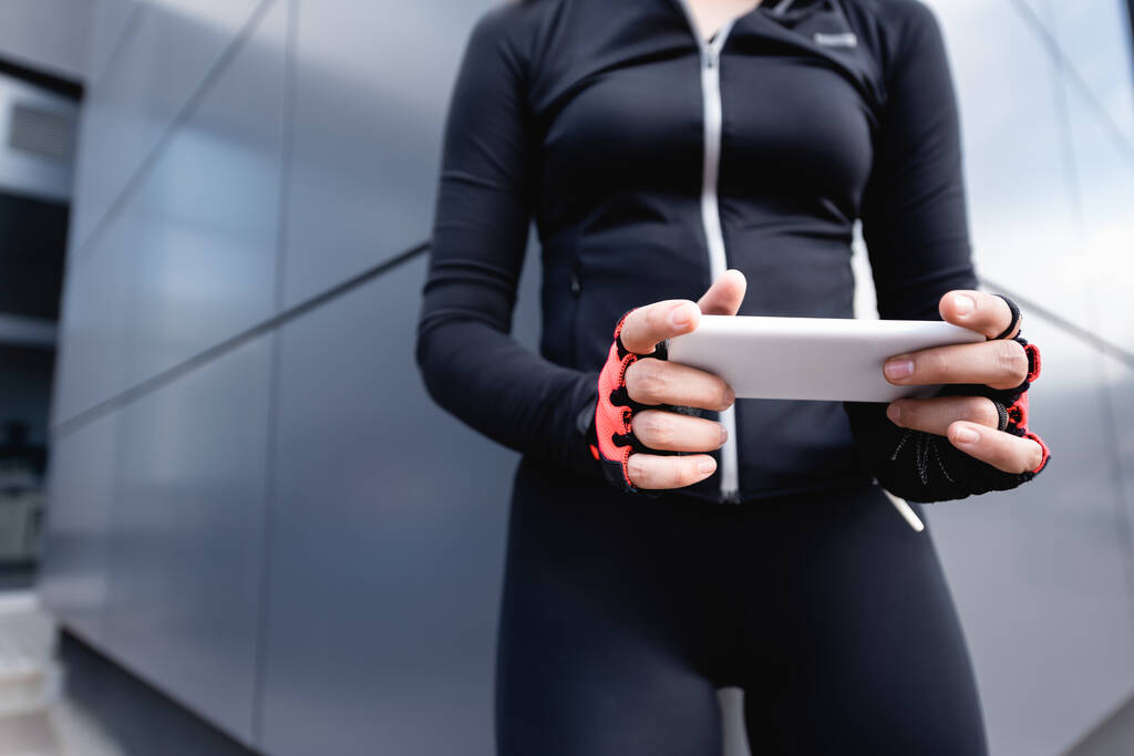 cropped view of woman in sportswear holding smartphone  - Photo, Image