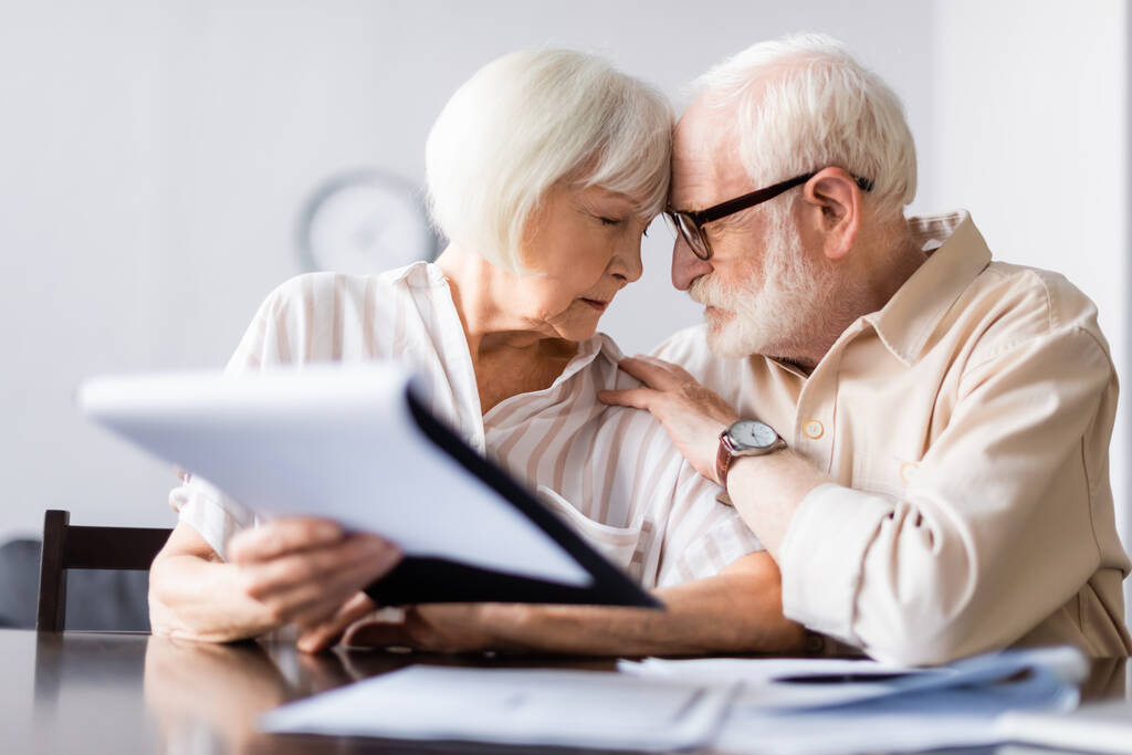 Válogatott fókusz a férfi átöleli idősebb feleség közel dokumentumokat az asztalon  - Fotó, kép
