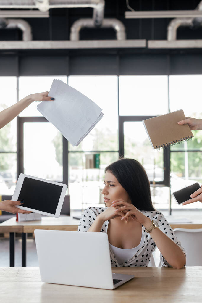 üzletasszony ül közel munkatársak kezében kütyü üres képernyő, notebook és papírok  - Fotó, kép