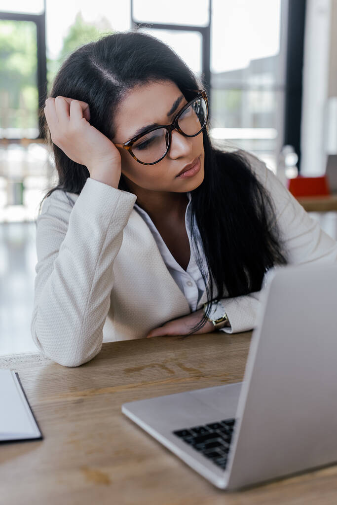 selektywne skupienie zmęczonej bizneswoman w okularach patrząc na laptopa  - Zdjęcie, obraz