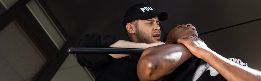 cultura panorâmica de policial em cap segurando bastão enquanto detendo homem afro-americano, conceito de racismo
  - Foto, Imagem