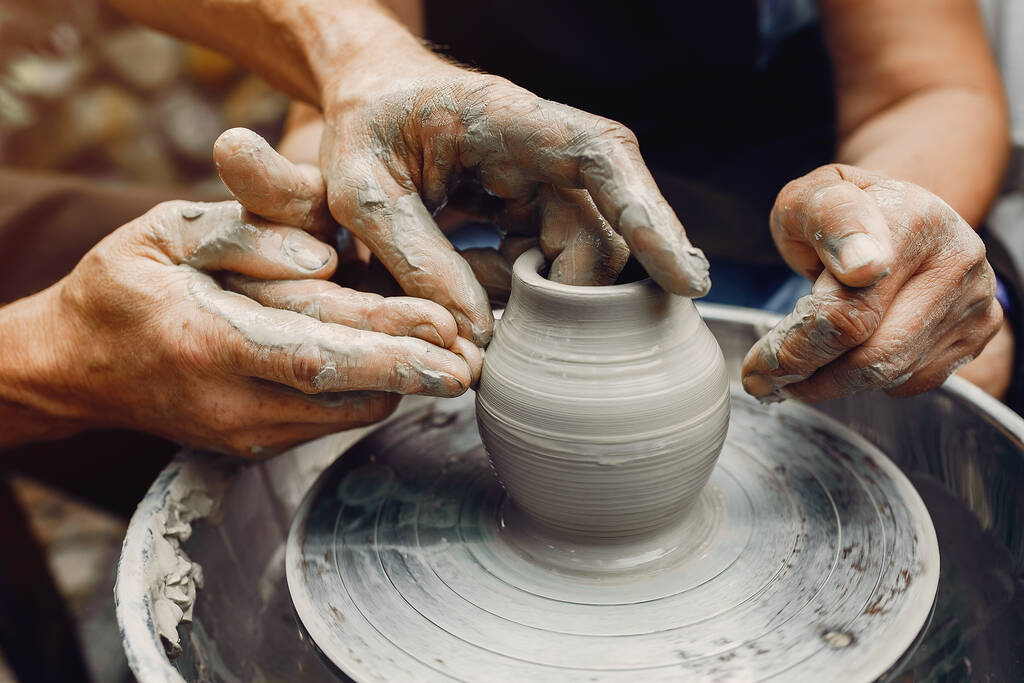 La abuela con los nietos fabrican los cántaros en la cerámica
 - Foto, Imagen