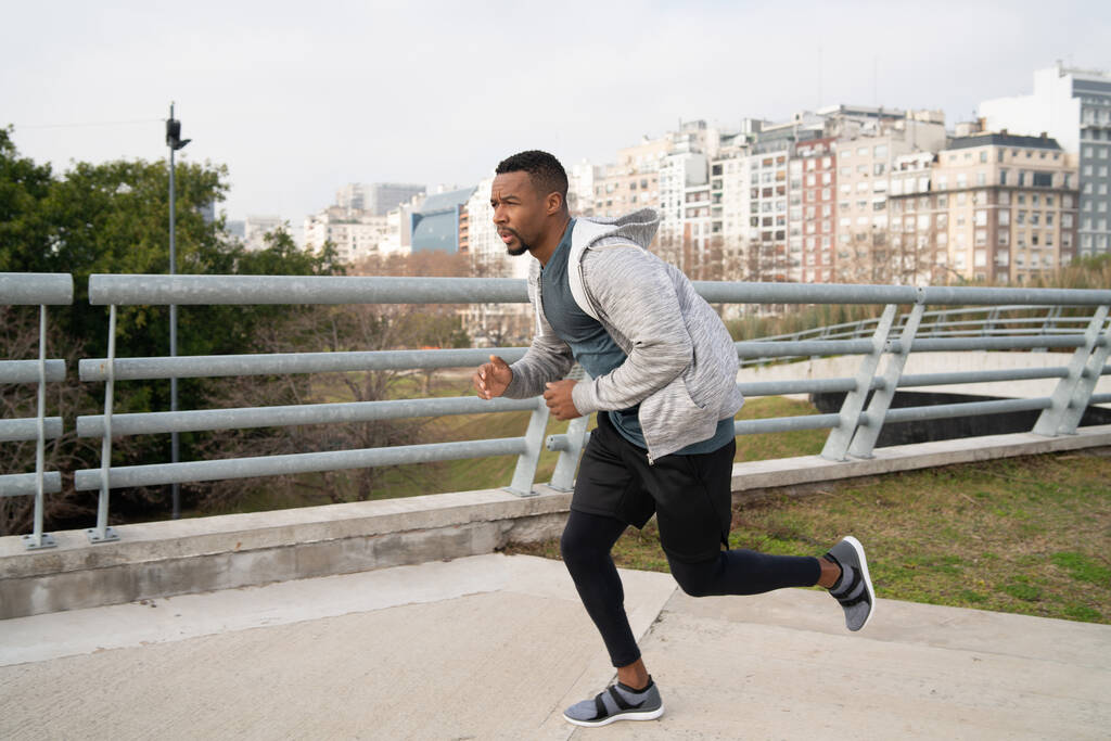 Porträt eines athletischen Mannes, der draußen auf der Straße läuft. Sport, Fitness und gesunder Lebensstil. - Foto, Bild