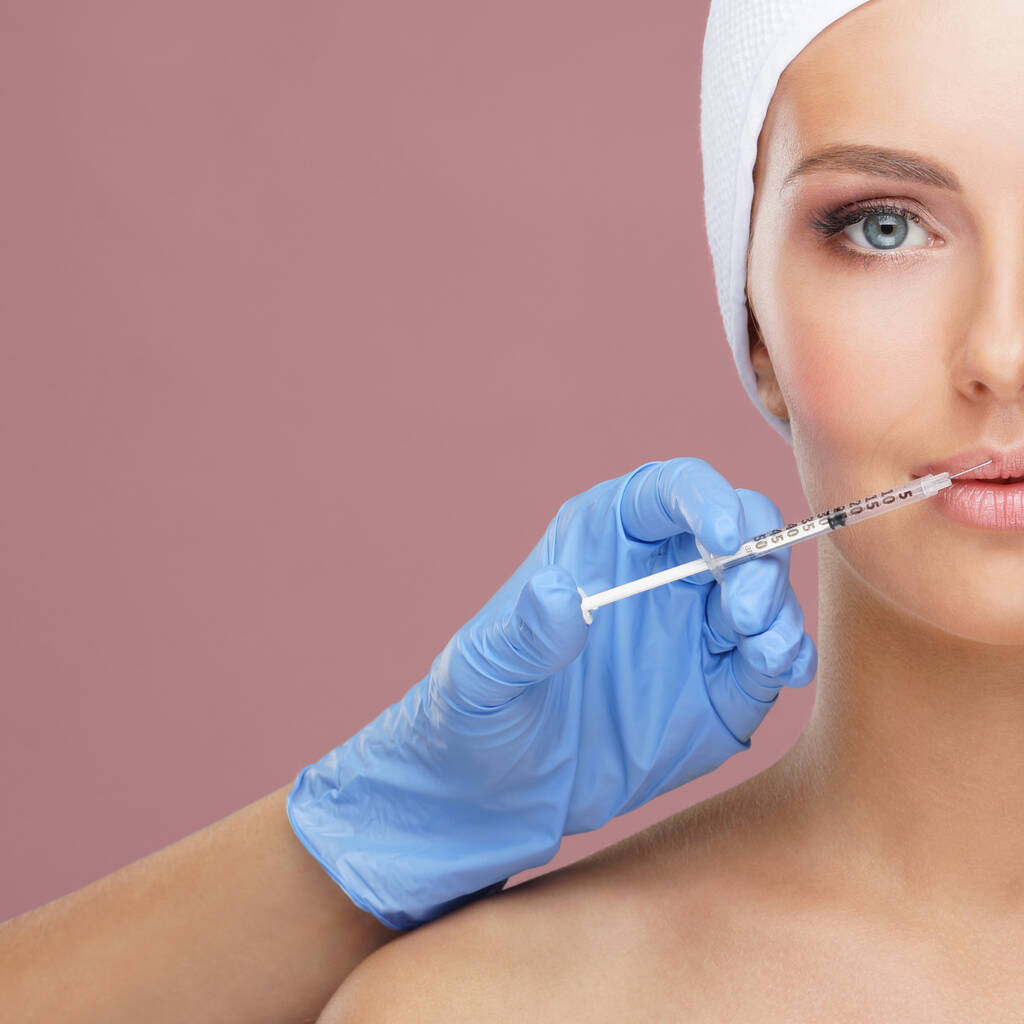 Arzt spritzt einer jungen Frau eine Spritze ins schöne Gesicht. Plastische Chirurgie, Hautstraffung und ästhetisches Medizinkonzept. - Foto, Bild