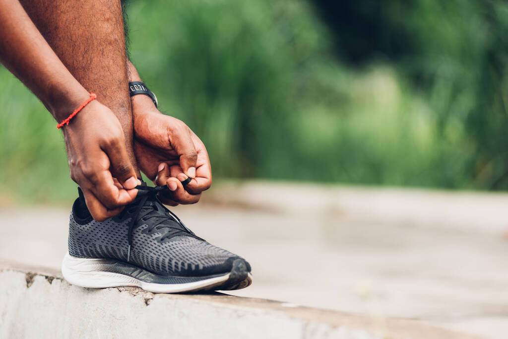 Закройте азиатский спортивный бегун черный мужчина носить часы стоять шаг по тропинке, пытаясь шнурки бег обувь готовится к бегу и запустить открытый парк здоровья улице, здоровые упражнения тренировки концепции - Фото, изображение
