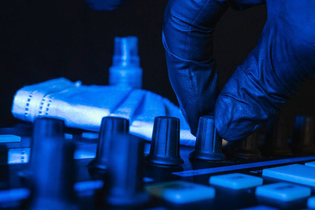Ein DJ wechselt die Melodie auf seinem Resonanzboden mit schwarzen Handschuhen und medizinischer Maske im Hintergrund - Foto, Bild