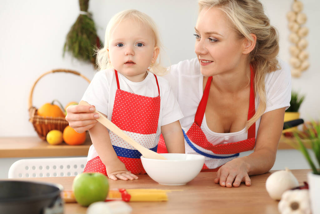 Mamma felice e figlioletta che cucinano in cucina. Trascorrere del tempo tutti insieme, concetto di divertimento in famiglia - Foto, immagini