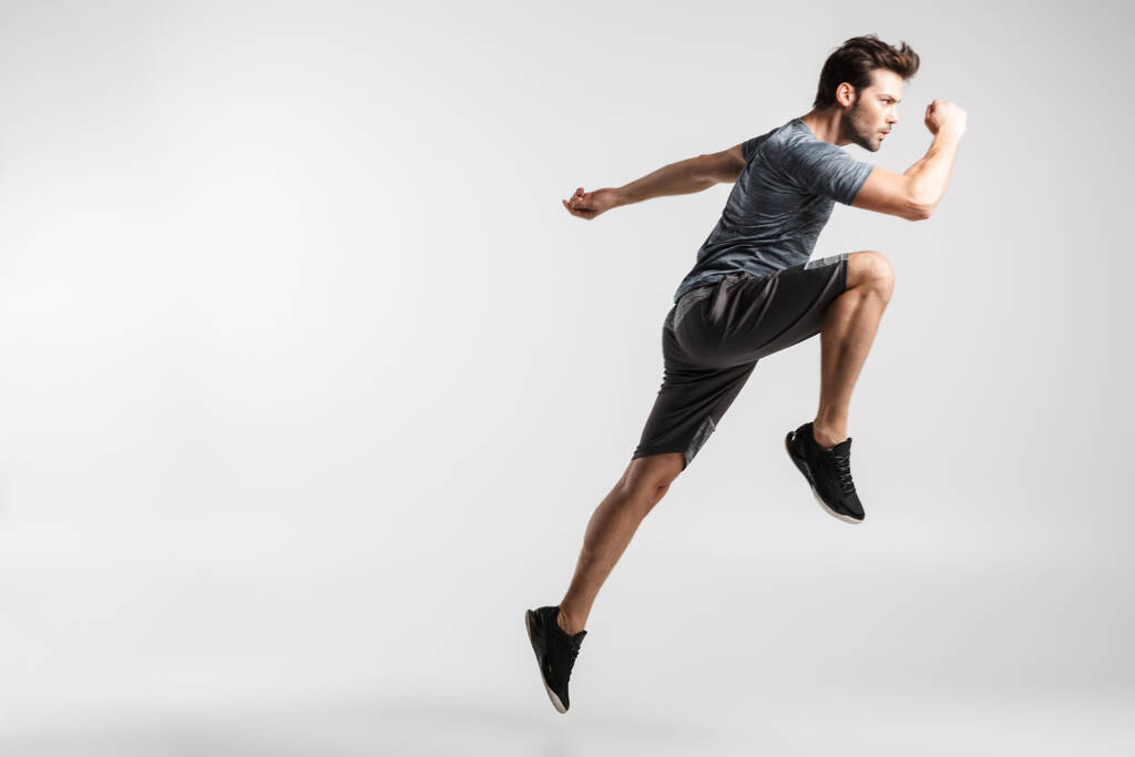 Imagen de un joven atlético en ropa deportiva haciendo ejercicio mientras hace ejercicio aislado sobre fondo blanco
 - Foto, imagen