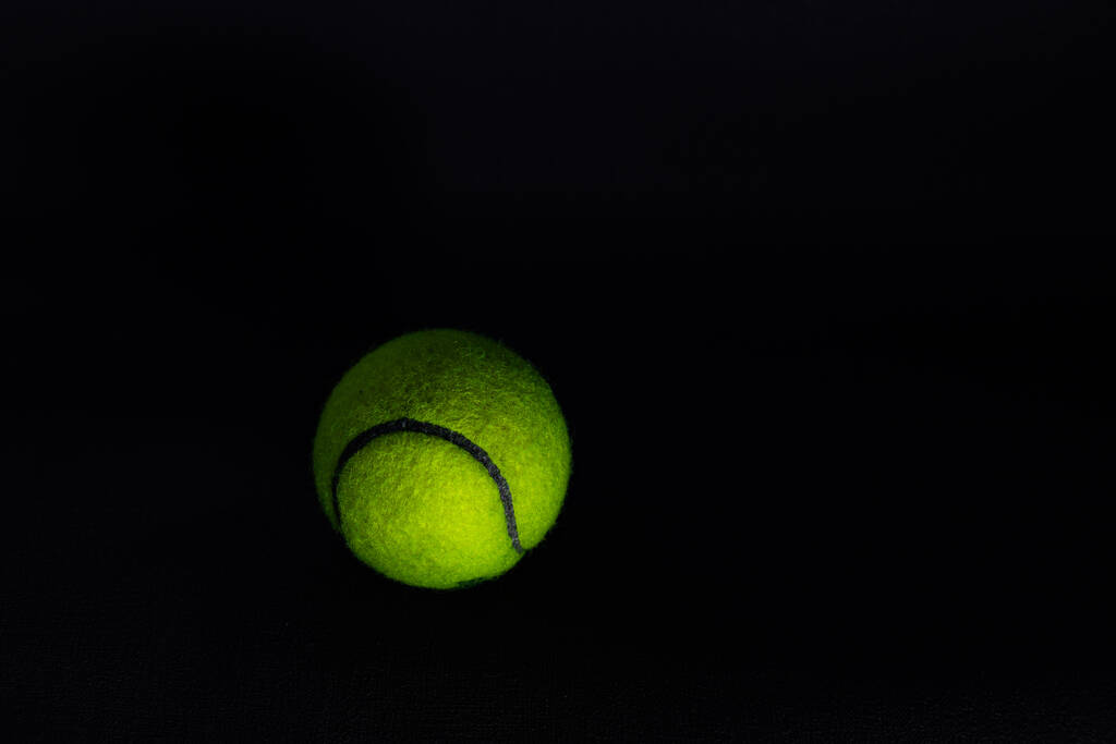 tenisz labda elszigetelt sötét háttérrel kemény fényben - Fotó, kép