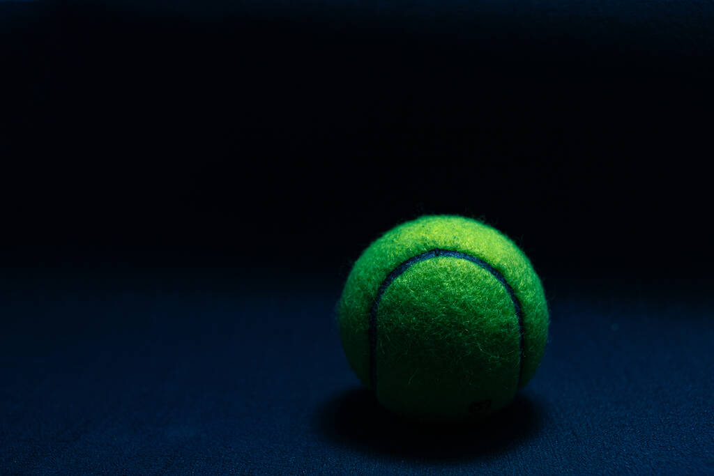 Tenis topu koyu arkaplanda koyu ışıkta izole edildi - Fotoğraf, Görsel