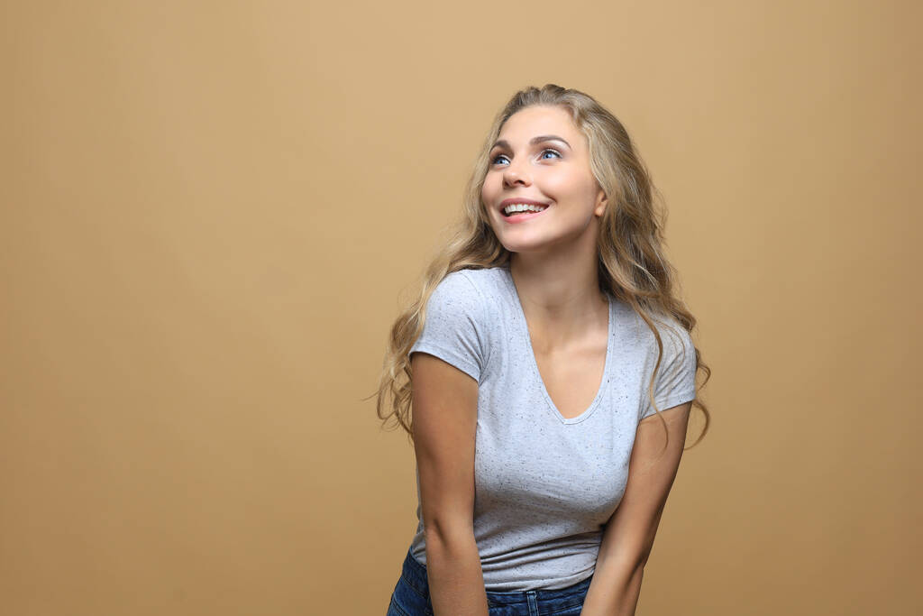 Obrázek šťastné mladé ženy stojící izolované přes béžové stěny pozadí - Fotografie, Obrázek