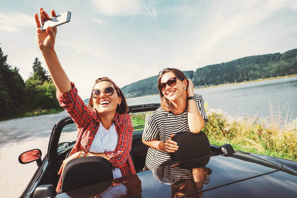 Kaksi naispuolista ystävää ottavat selfien valokuvan automatkansa aikana - Valokuva, kuva