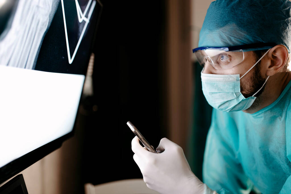 Ортопед-травматолог мужского пола касается сенсорного экрана рентгеном кости - Фото, изображение