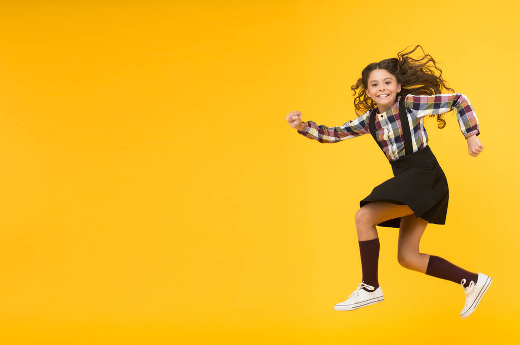 Glücklicher Kindertag. Jump-Konzept. Einbruch. Spüren Sie innere Energie. Mädchen mit langen Haaren springen auf gelbem Hintergrund. Unbeschwerter Sommerurlaub für Kinder. Zeit für Spaß. Aktive Mädchen spüren Freiheit. Spaß und Springen - Foto, Bild