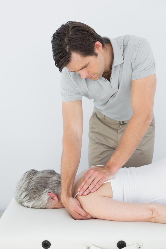 Fisioterapeuta do sexo masculino massageando o ombro de uma mulher idosa
 - Foto, Imagem