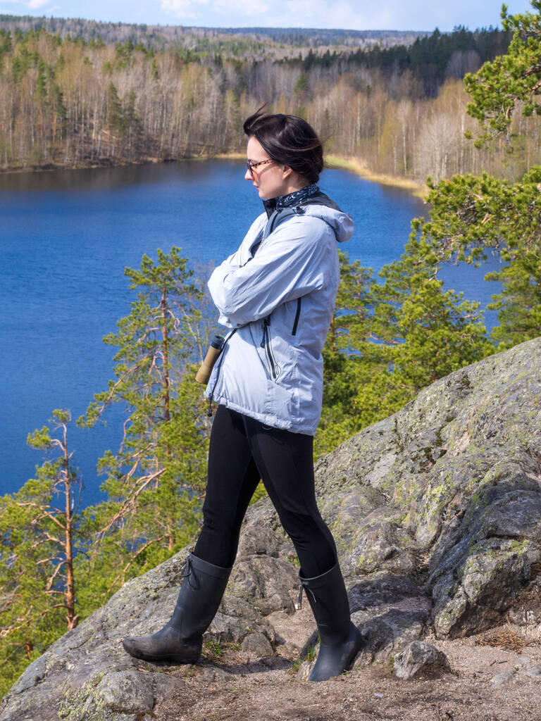 Девушка-туристка стоит на скале и смотрит на озеро - Фото, изображение