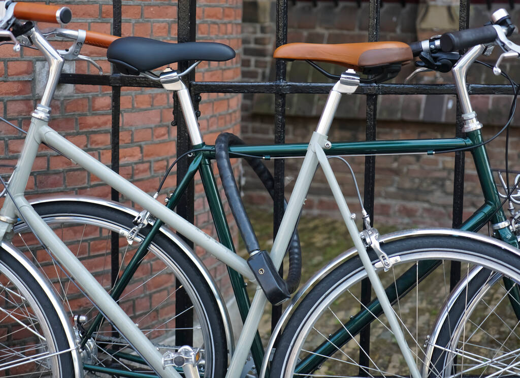dos bicicletas clásicas de pie sobre cerradura en la valla de metal negro. calle europea. bicicleta moderna. Haag, Países Bajos. - Foto, imagen