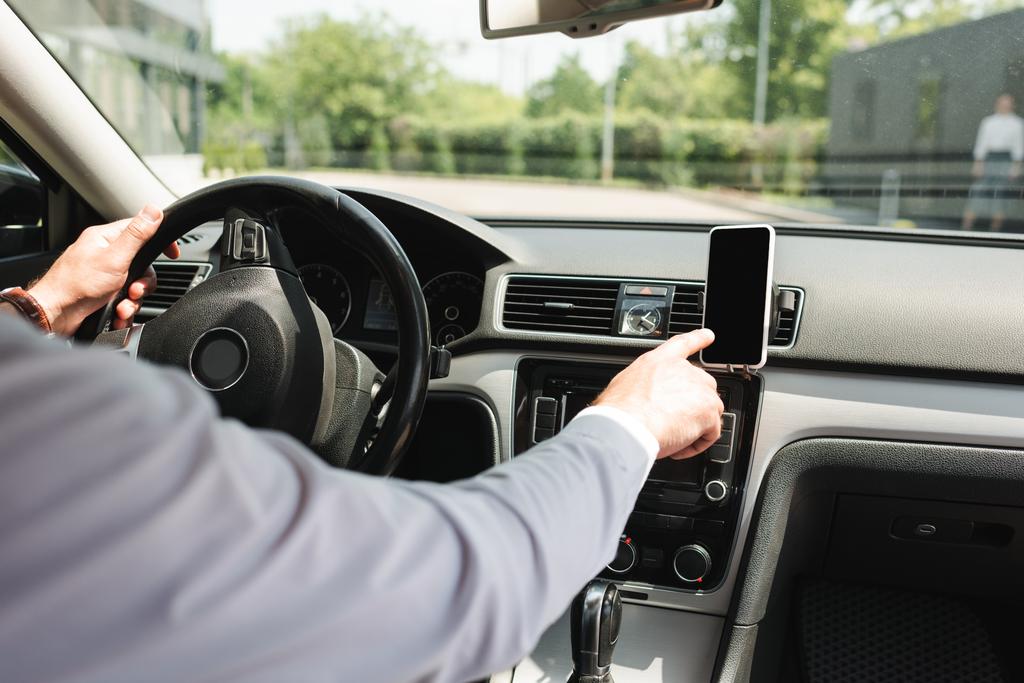 Vista recortada del hombre de negocios utilizando el teléfono inteligente mientras conduce auto
   - Foto, Imagen