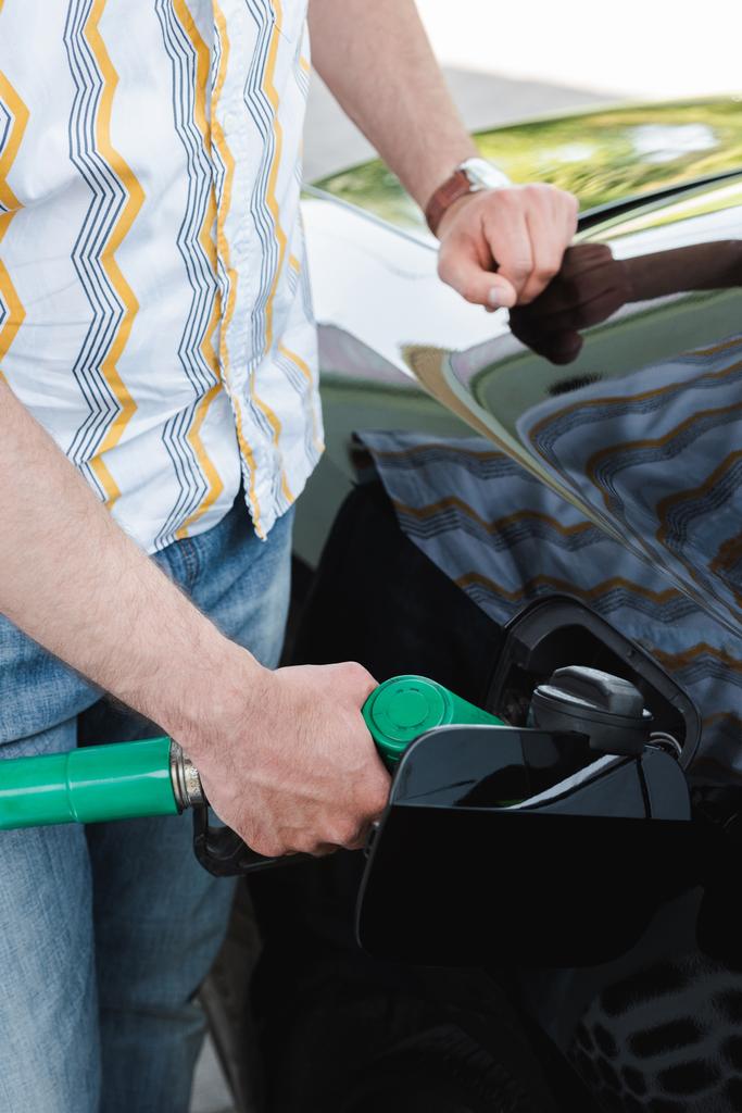 Vista ritagliata dell'uomo che alimenta auto sul distributore di benzina  - Foto, immagini