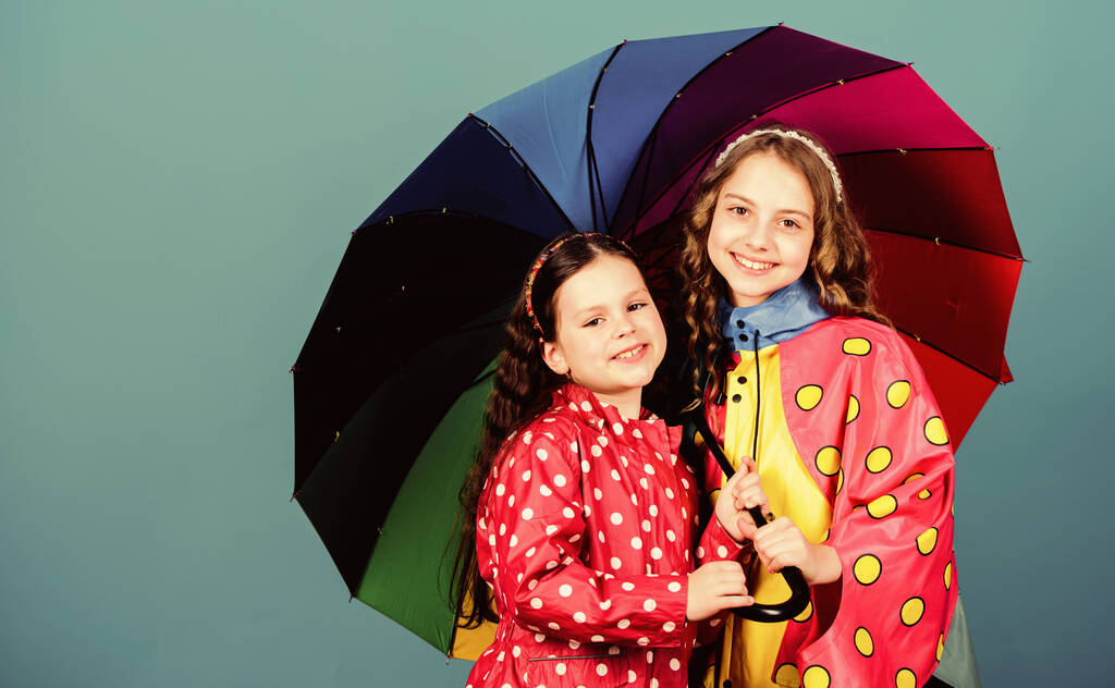 cheerful hipster children, sisterhood. rain protection. Rainbow. autumn fashion. happy little girls with colorful umbrella. family bonds. Little girls in raincoat. Important part of camping - Photo, Image