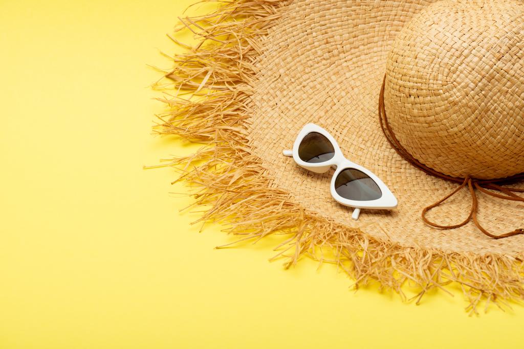 Strohhut und stylische Zuckerbrille auf gelbem Hintergrund - Foto, Bild