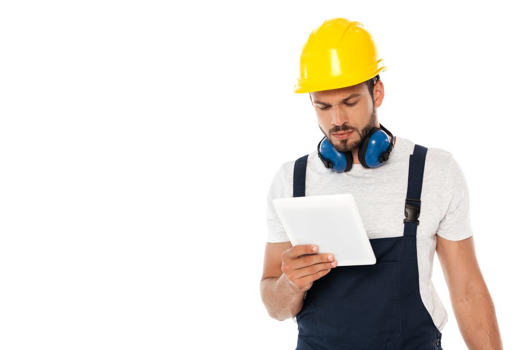 Arbeiter mit Hut und Ohrenschützer halten digitales Tablet isoliert auf weißem Grund - Foto, Bild