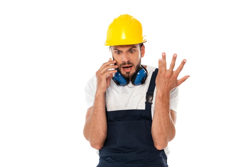 Obrero enojado haciendo gestos mientras habla en un teléfono inteligente aislado en blanco
 - Foto, imagen