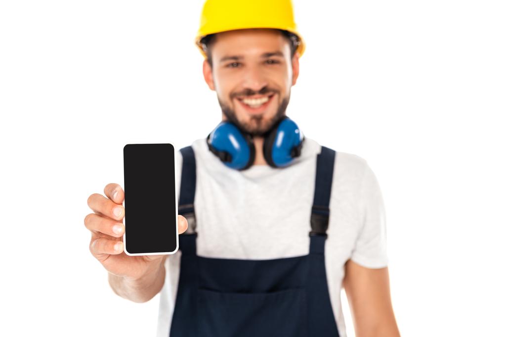 Beyaz ekranda boş ekranlı akıllı telefon gösteren gülümseyen işçinin seçici odağı - Fotoğraf, Görsel