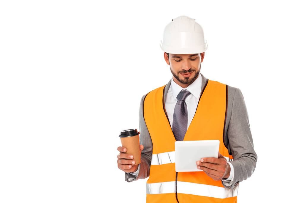 Przystojny inżynier w garniturze i twardym kapeluszu trzymający kawę na wynos i cyfrowy tablet na białym - Zdjęcie, obraz