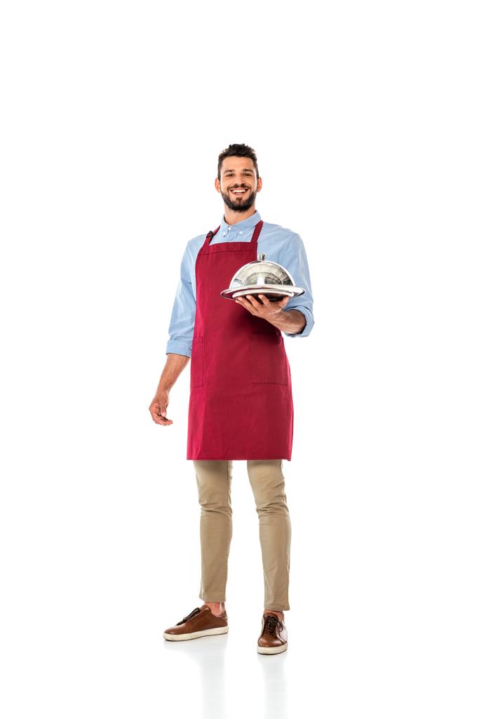 Handsome smiling waiter holding metal tray and dish cover on white background - Photo, Image