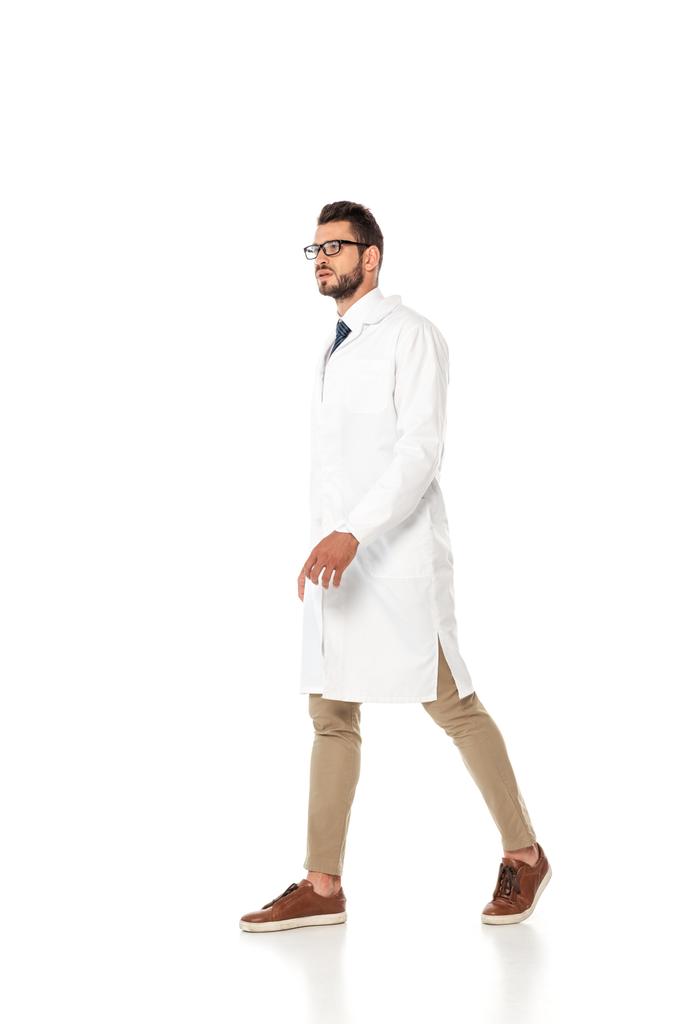 Doctor en bata blanca y anteojos caminando sobre fondo blanco
 - Foto, Imagen