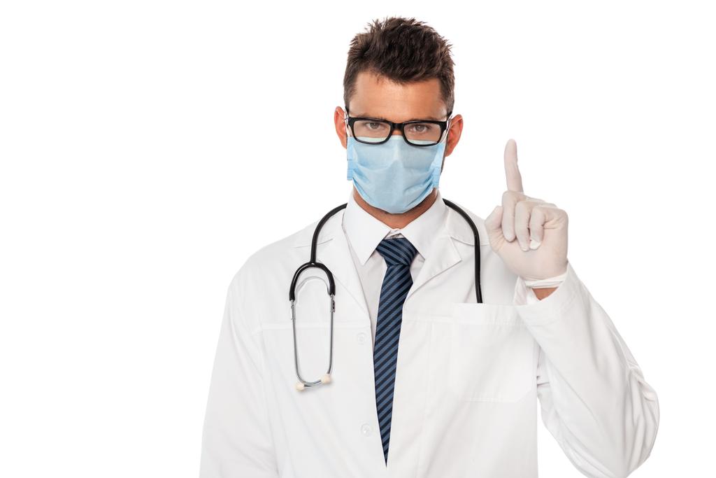 Tıbbi maskeli doktor, steteskopla beyaz üzerine parmak işareti yapıyor. - Fotoğraf, Görsel