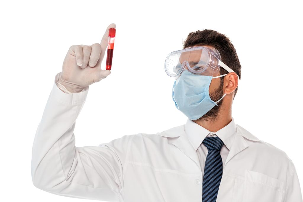 Doctor in medical mask and protective goggles holding test tube with blood sample isolated on white - Photo, Image