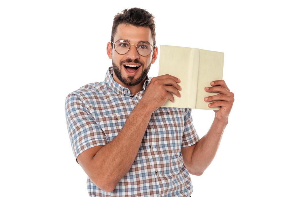Cheerful nerd in eyeglasses holding open book isolated on white - Photo, Image