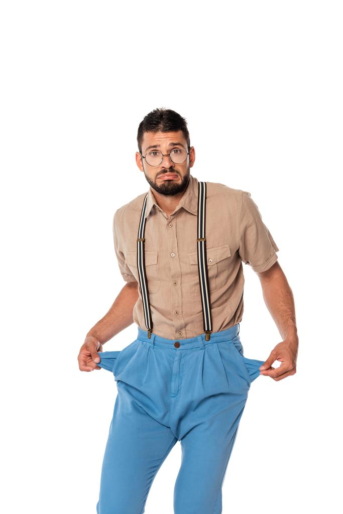 Confused nerd looking at camera while showing empty pockets of pants isolated on white - Photo, Image